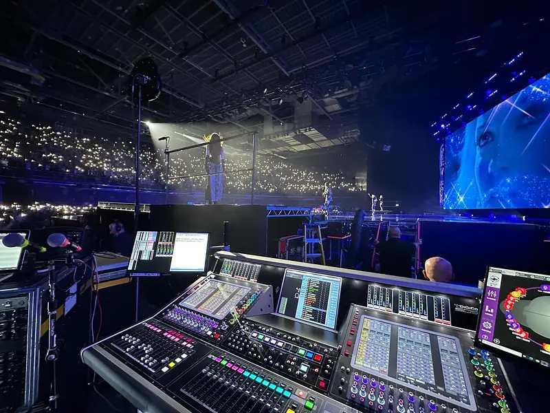 DiGiCo SD5 console in the foreground with a singer on stage and a crowd lit by phone lights